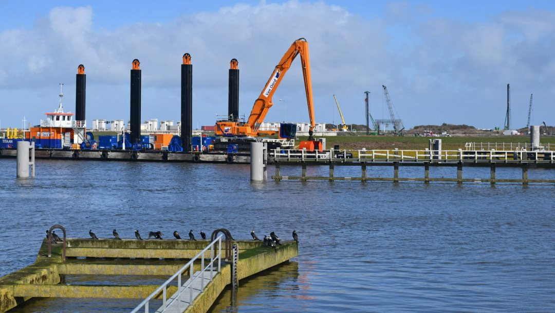 A crane on a pontoon placing first Levvel armour blocks on closure dam Afsluitdijk, the Netherlands