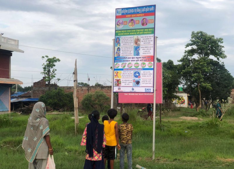 Khadak citizens in Nepal read hygiene messages on a hoarding board
