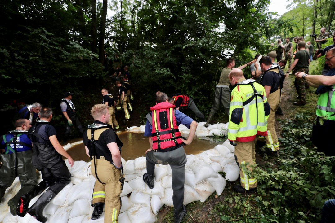Rescue workers prevent seepage near a levee of the Meuse in July 2021