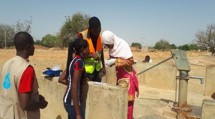 Woman collects drinking water at pump in Burkina Faso