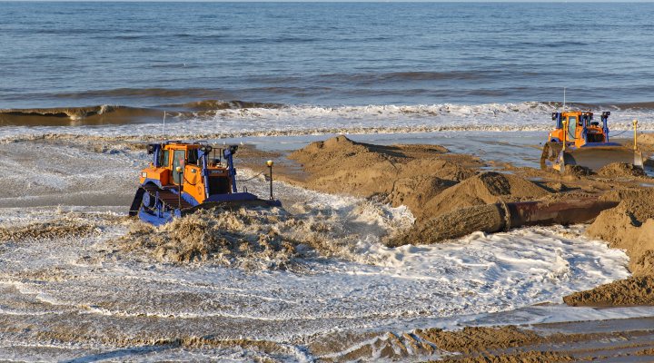 Bulldozers sandscaping at Bacton beach, East Anglia, UK in 2019