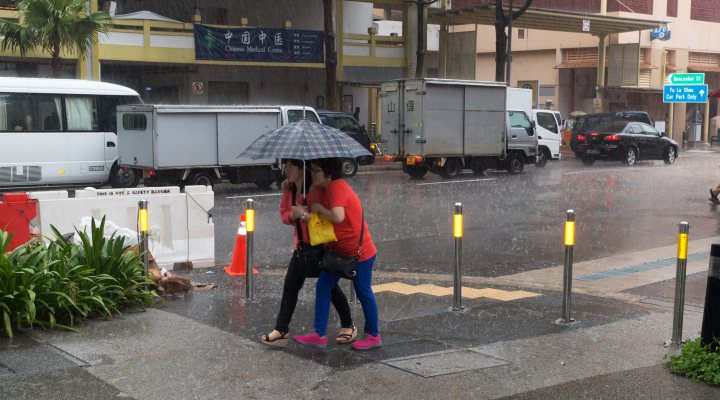 Two women sharing an umbrella during torrential afternoon storm.