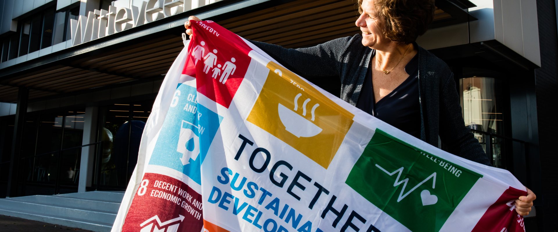CEO Karin Sluis of Wittenveen+Bos holds a flag of the UN Sustainable Development Goals