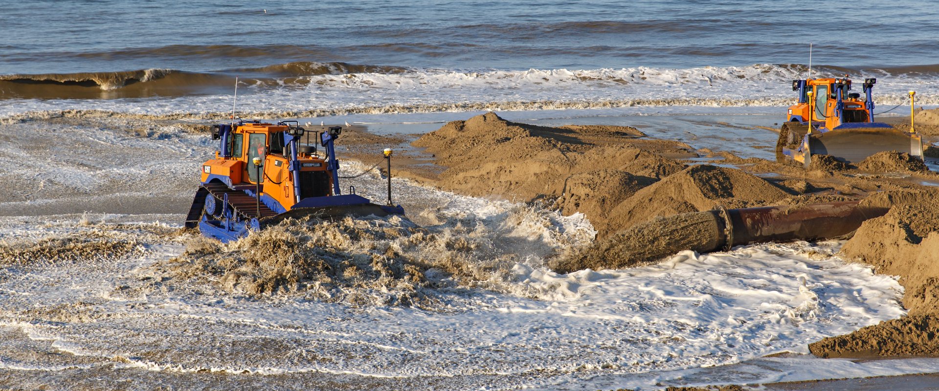 Bulldozers sandscaping at Bacton beach, East Anglia, UK in 2019